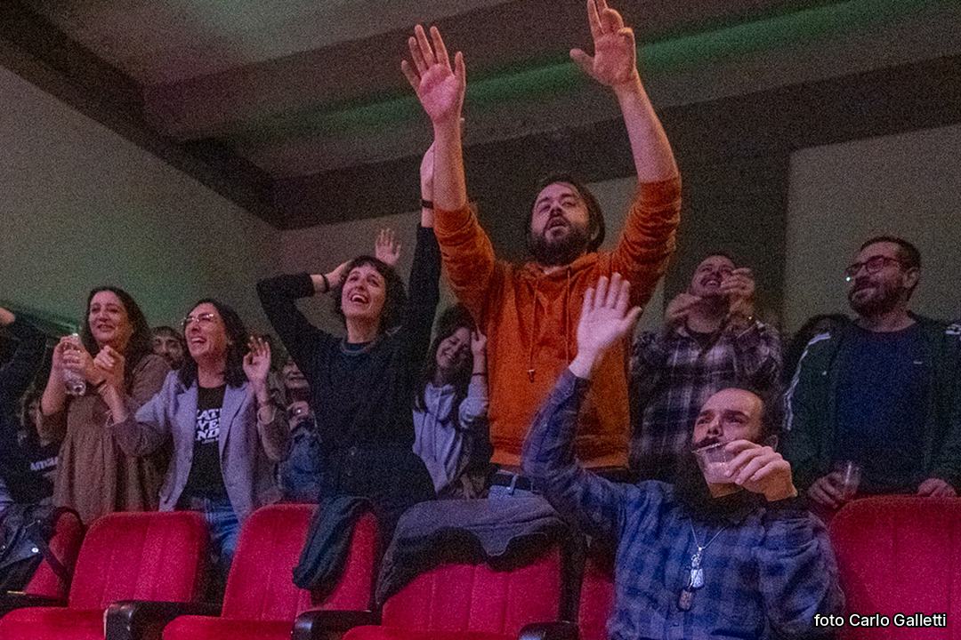 Il pubblico in sala, in piedi con le braccia alzate. Foto di Carlo Galletti.